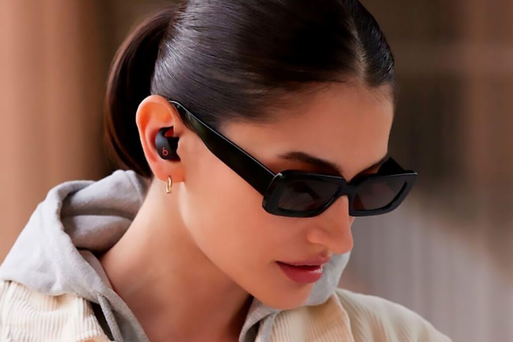 Lady with sunglasses wearing Beats Fit Pro earbuds to illustrate a half-price deal.